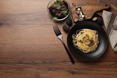 Photo of Tasty spaghetti with truffle served on wooden table, flat lay. Space for text
