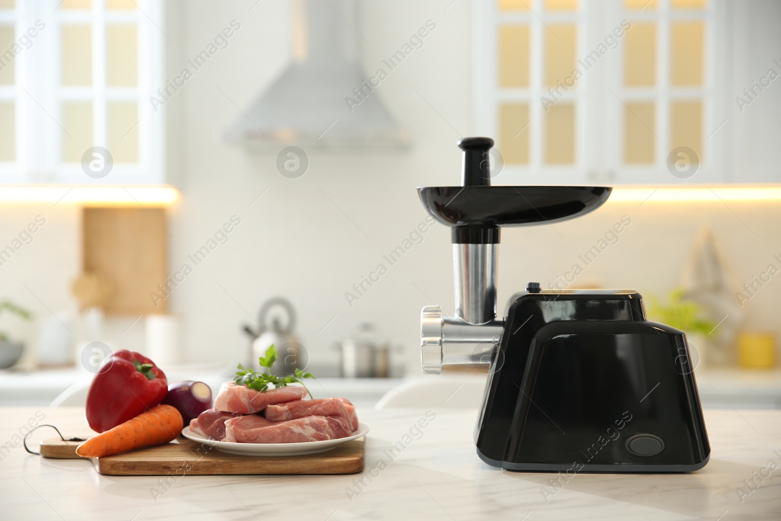 Photo of Modern meat grinder and products on white marble table in kitchen. Space for text