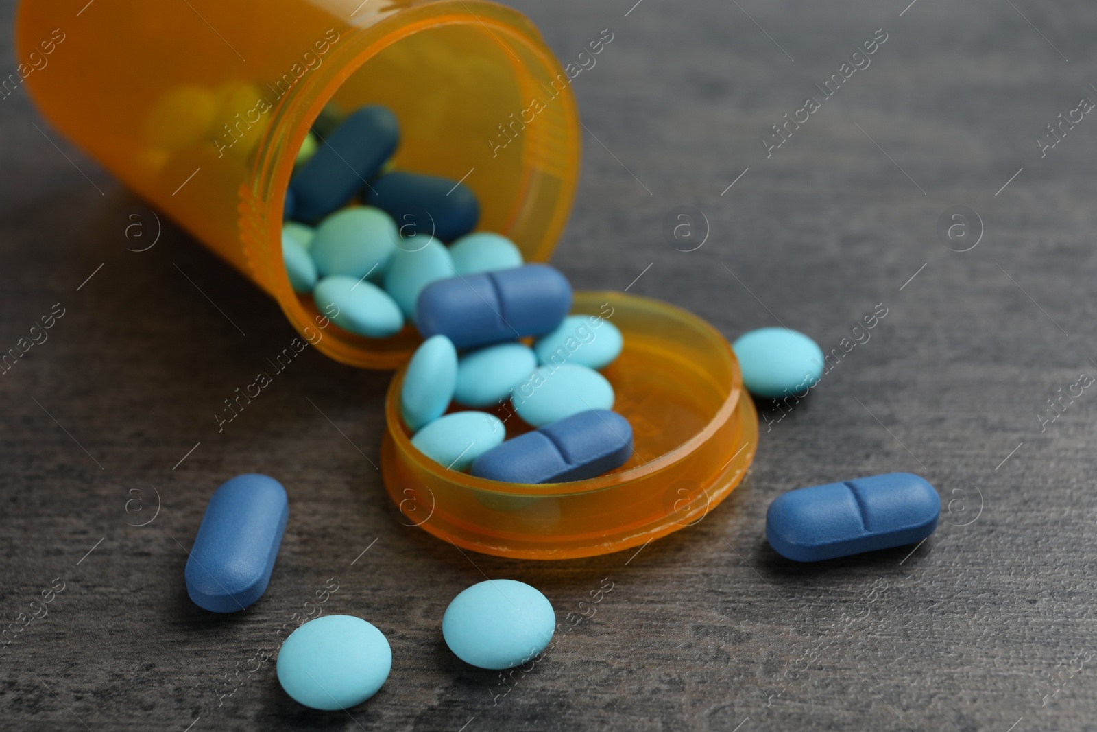 Photo of Container with different pills on grey background