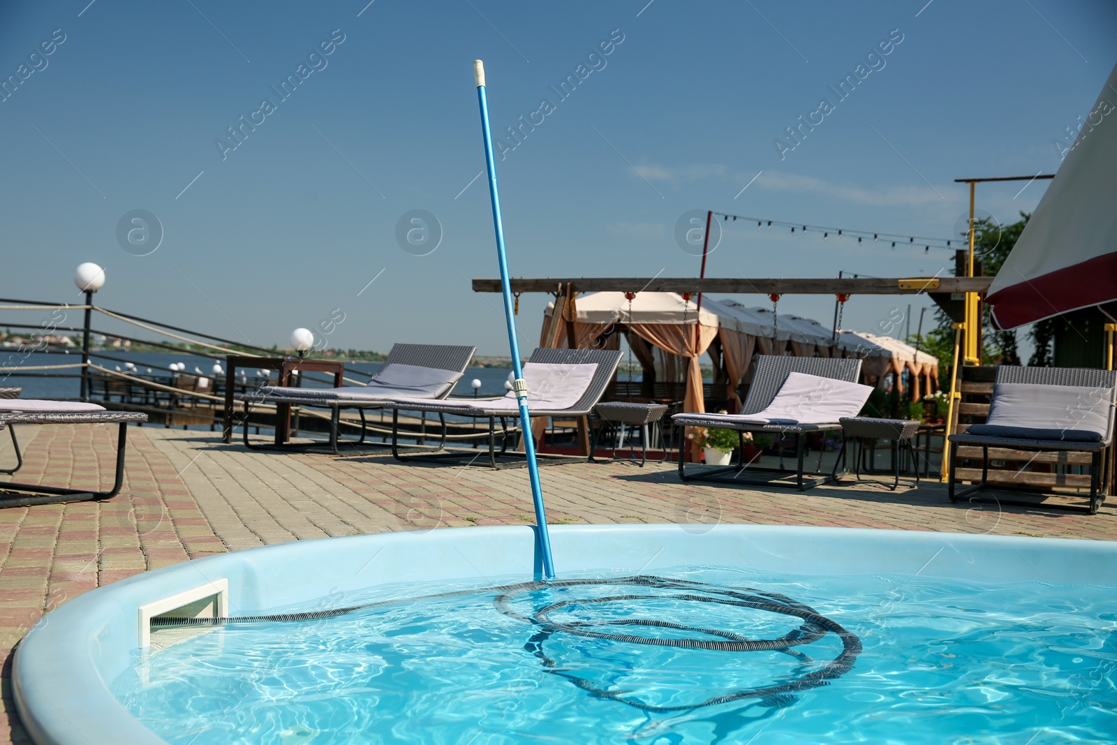 Photo of Cleaning outdoor swimming pool with underwater vacuum