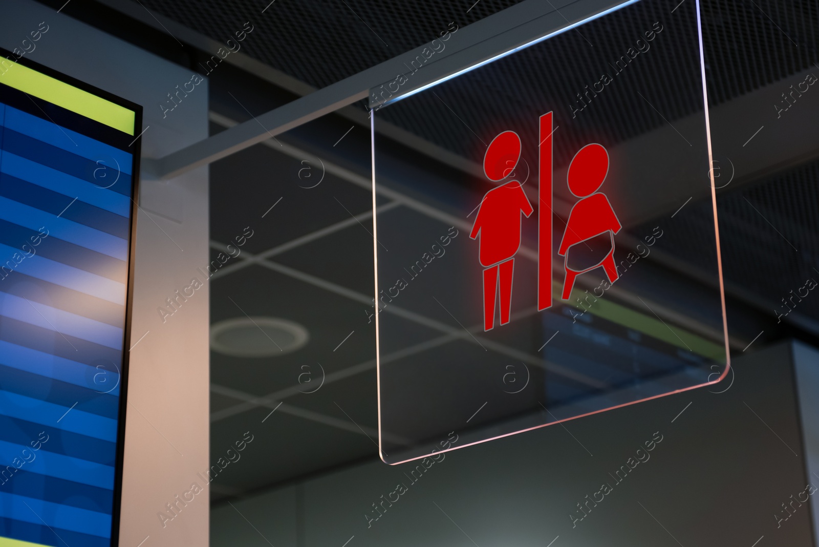 Image of Red public toilet sign on transparent glass hanging indoors