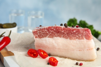 Photo of Composition with pork fatback and spices on white table against blue background