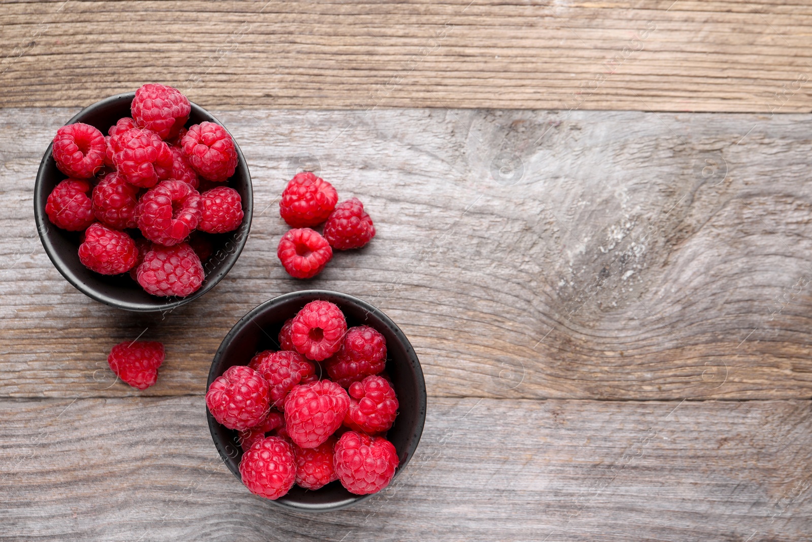 Photo of Tasty ripe raspberries on wooden table, flat lay. Space for text