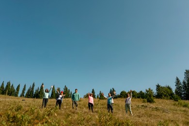 Group of happy tourists on hill in mountains, low angle view