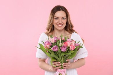 Photo of Happy young woman with bouquet of beautiful tulips on pink background