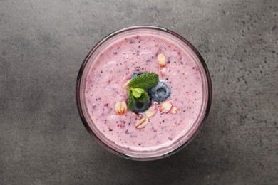 Photo of Glass of tasty blueberry smoothie with oatmeal on dark grey table, top view