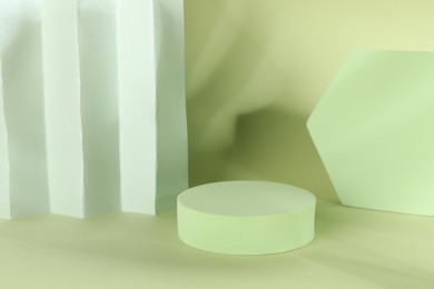 Photo of Presentation of product. Podiums, paper and shadows on light green background. Space for text