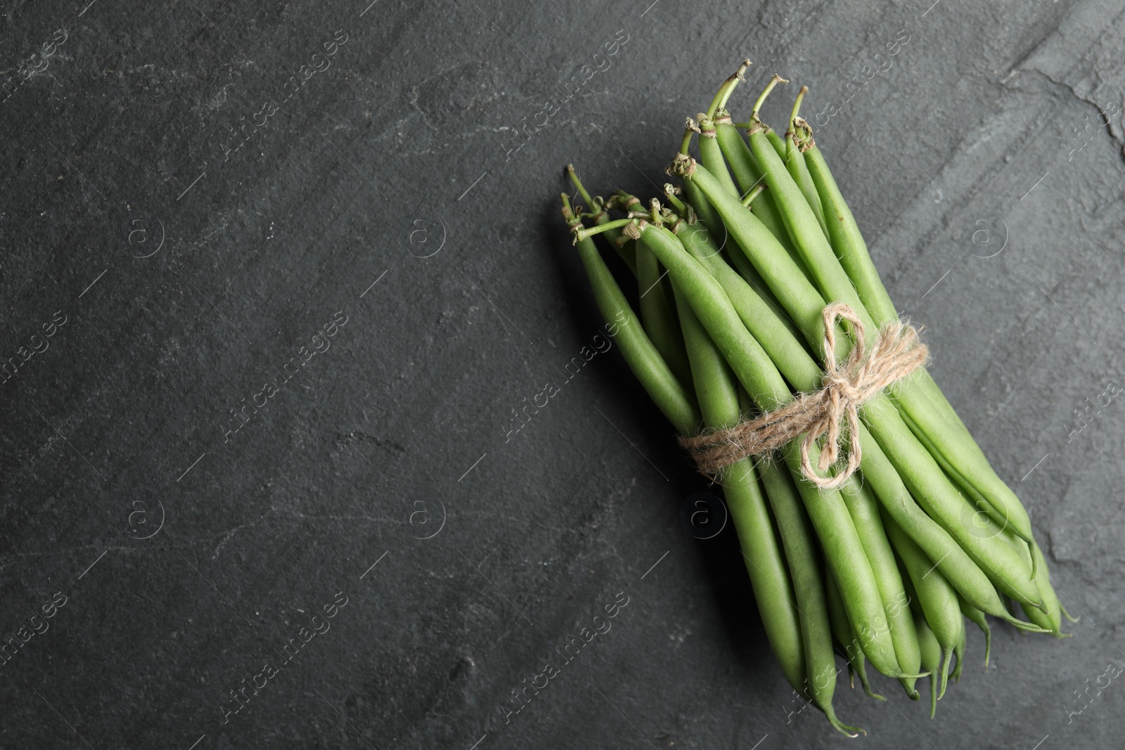 Photo of Fresh green beans on black table, top view. Space for text