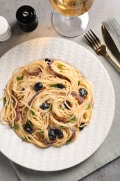 Photo of Delicious pasta with anchovies, olives and parmesan cheese served on grey table, flat lay