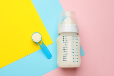 Photo of Feeding bottle with infant formula and powder on color background, flat lay