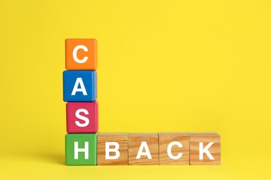 Photo of Word Cashback made with cubes on yellow background