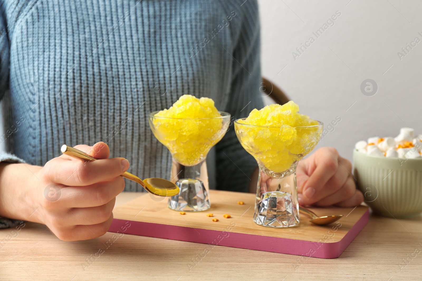 Photo of Woman eating tasty snow ice cream dessert at table, closeup