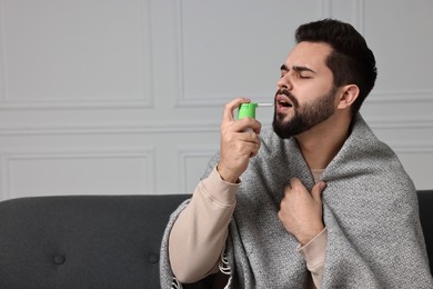 Photo of Young man using throat spray indoors. Space for text