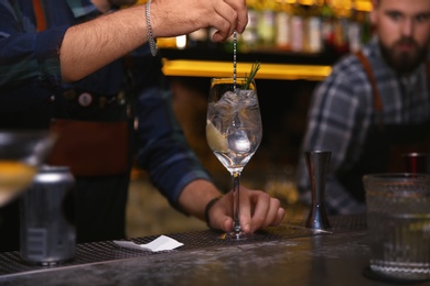 Bartender preparing tasty cocktail at counter in nightclub, closeup