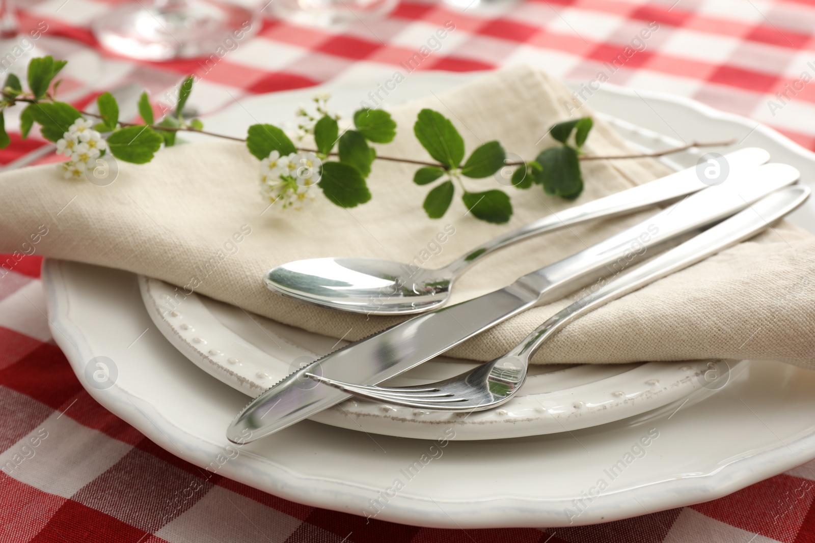 Photo of Stylish setting with cutlery, plates, napkin and floral decor on table, closeup