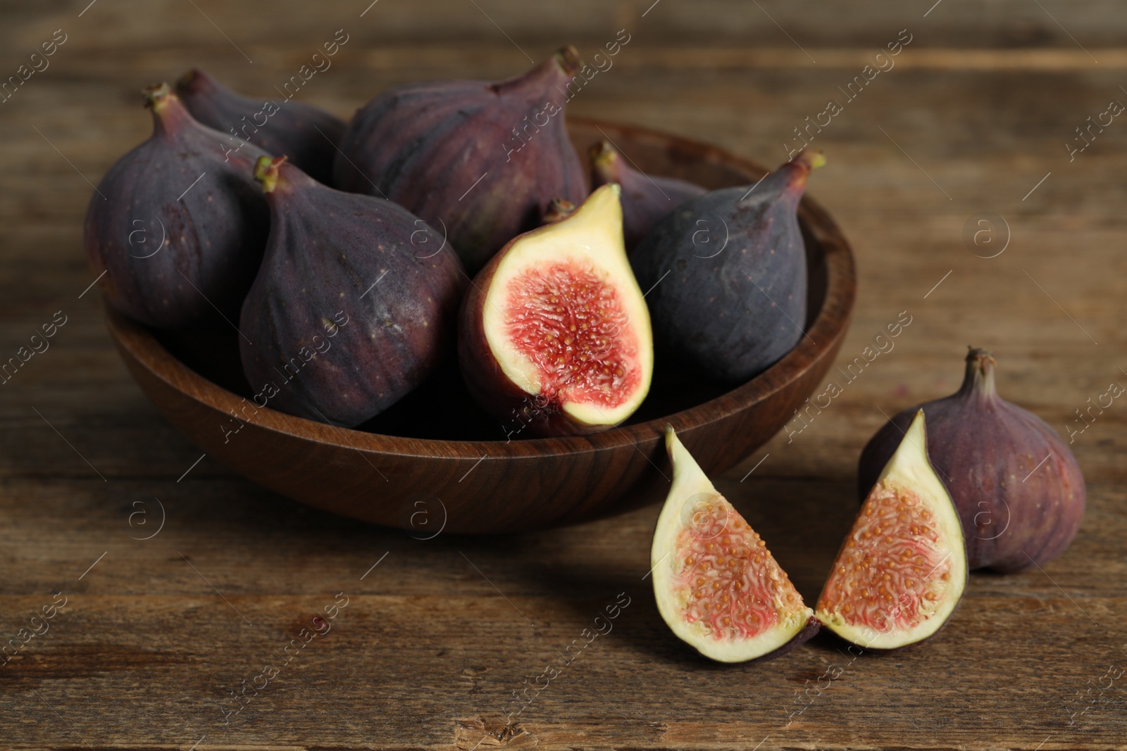 Photo of Whole and cut tasty fresh figs on wooden table