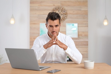 Photo of Portrait of handsome young man with laptop in office