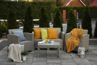 Photo of Beautiful rattan garden furniture, soft pillows and different decor elements in backyard