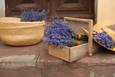 Photo of Beautiful lavender flowers and straw hat near building outdoors