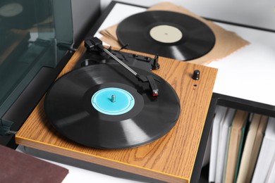 Photo of Stylish turntable with vinyl disc on table in room, closeup