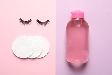 Photo of False eyelashes, cotton pads and makeup remover on color background, flat lay