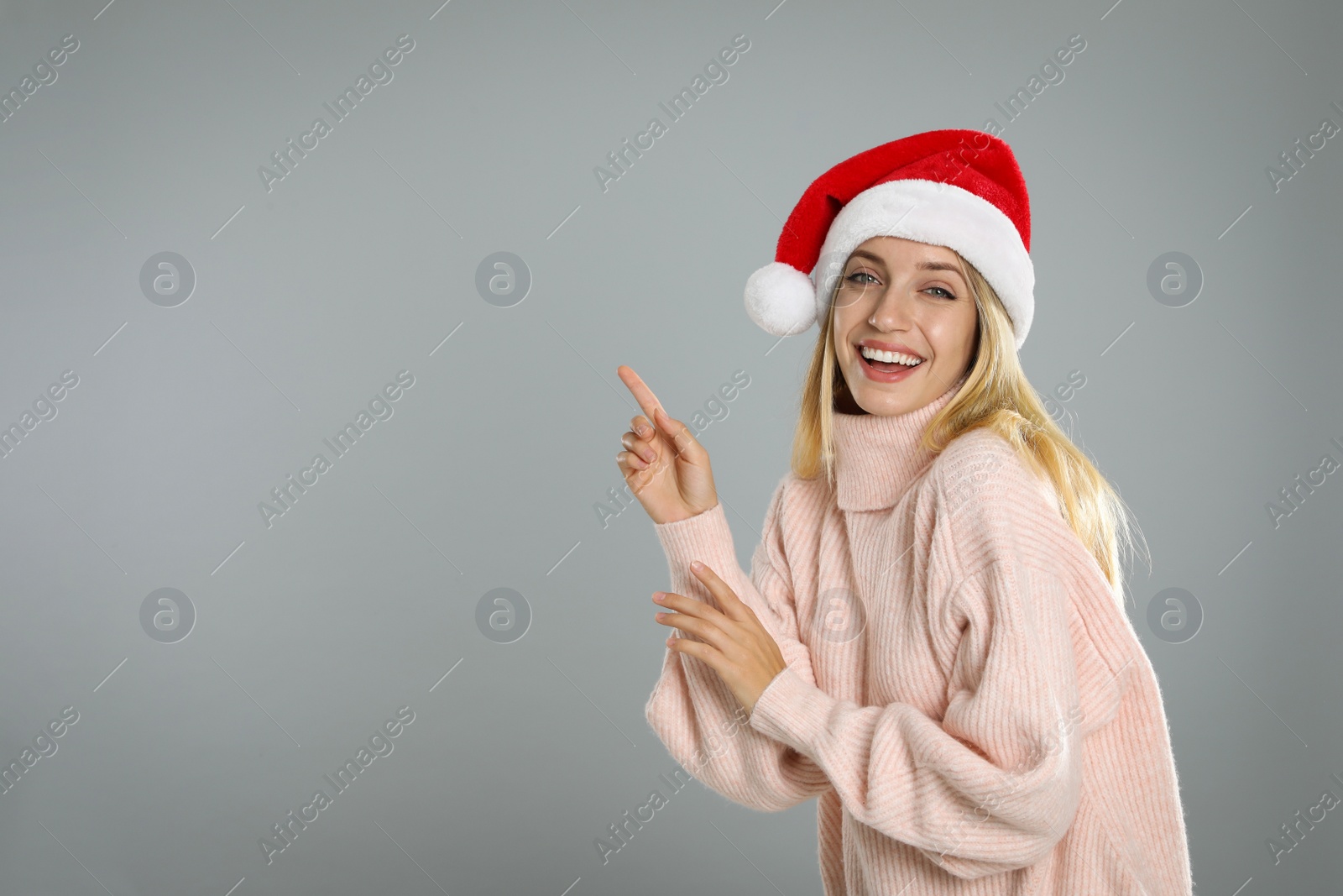 Photo of Happy woman in Santa hat on grey background, space for text. Christmas countdown