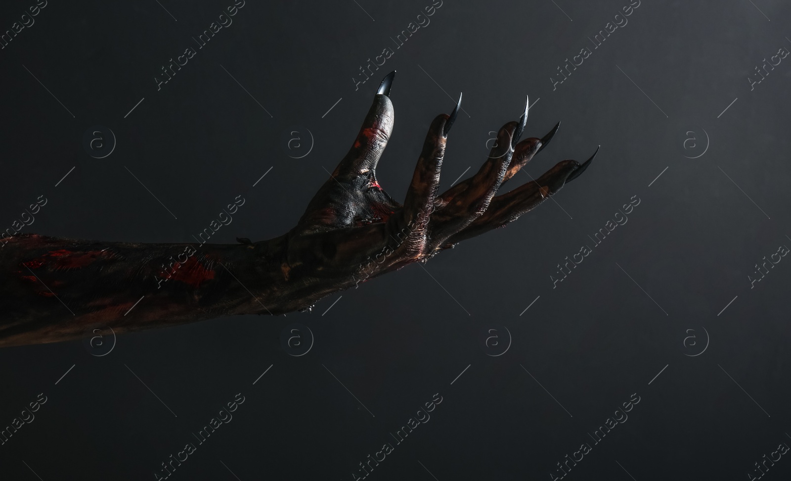 Photo of Scary monster on black background, closeup of hand. Halloween character