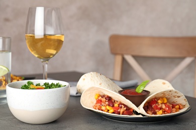 Plate with tasty chili con carne served in tortillas on gray table