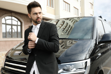 Handsome young man near modern car outdoors