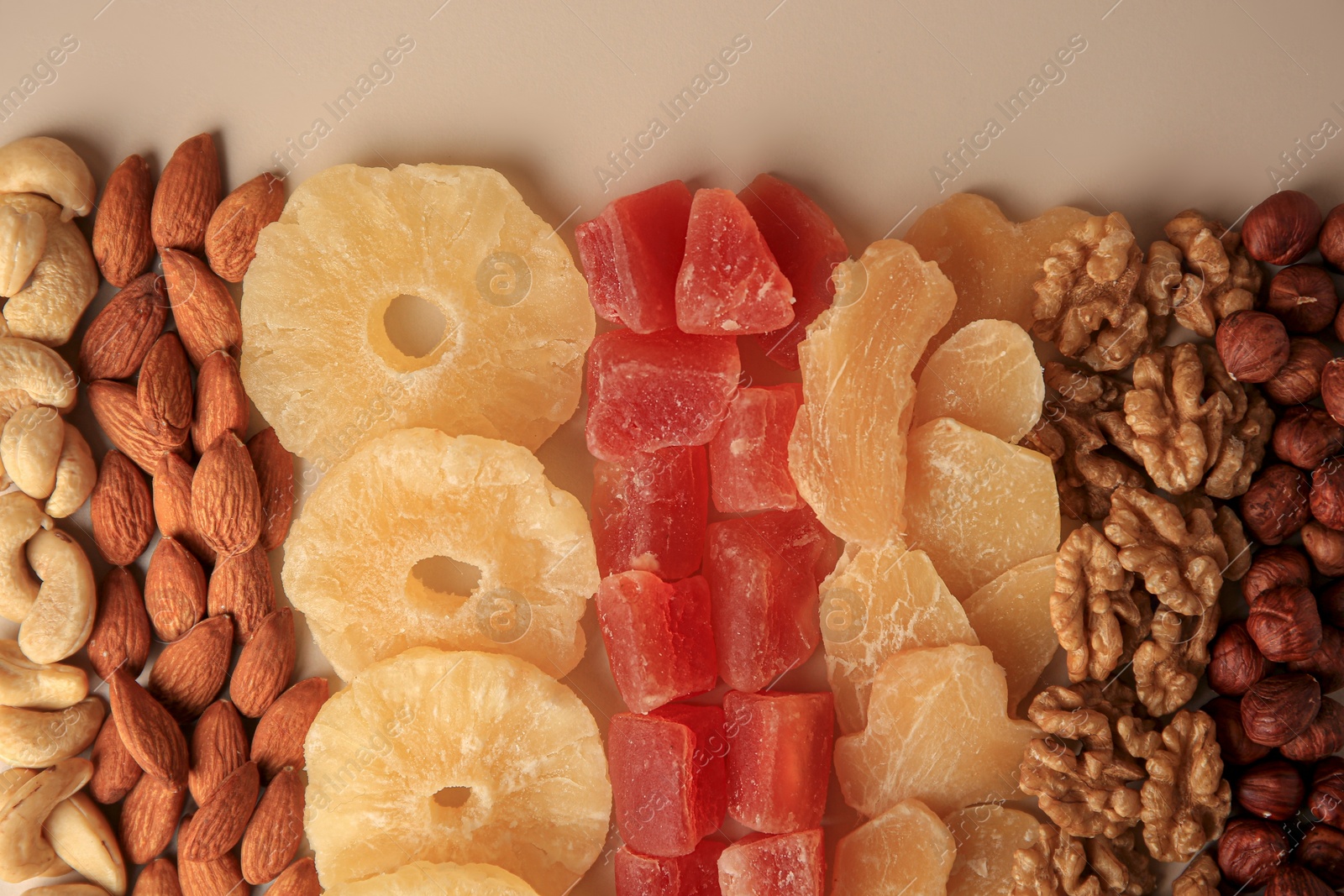 Photo of Different tasty nuts and dried fruits on beige background, flat lay