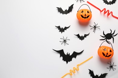 Flat lay composition with plastic pumpkin baskets and paper bats on white background, space for text. Halloween celebration