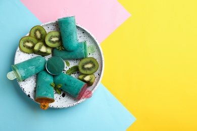 Photo of Plate with spirulina popsicles, mint and kiwi slices on color background, top view. Space for text