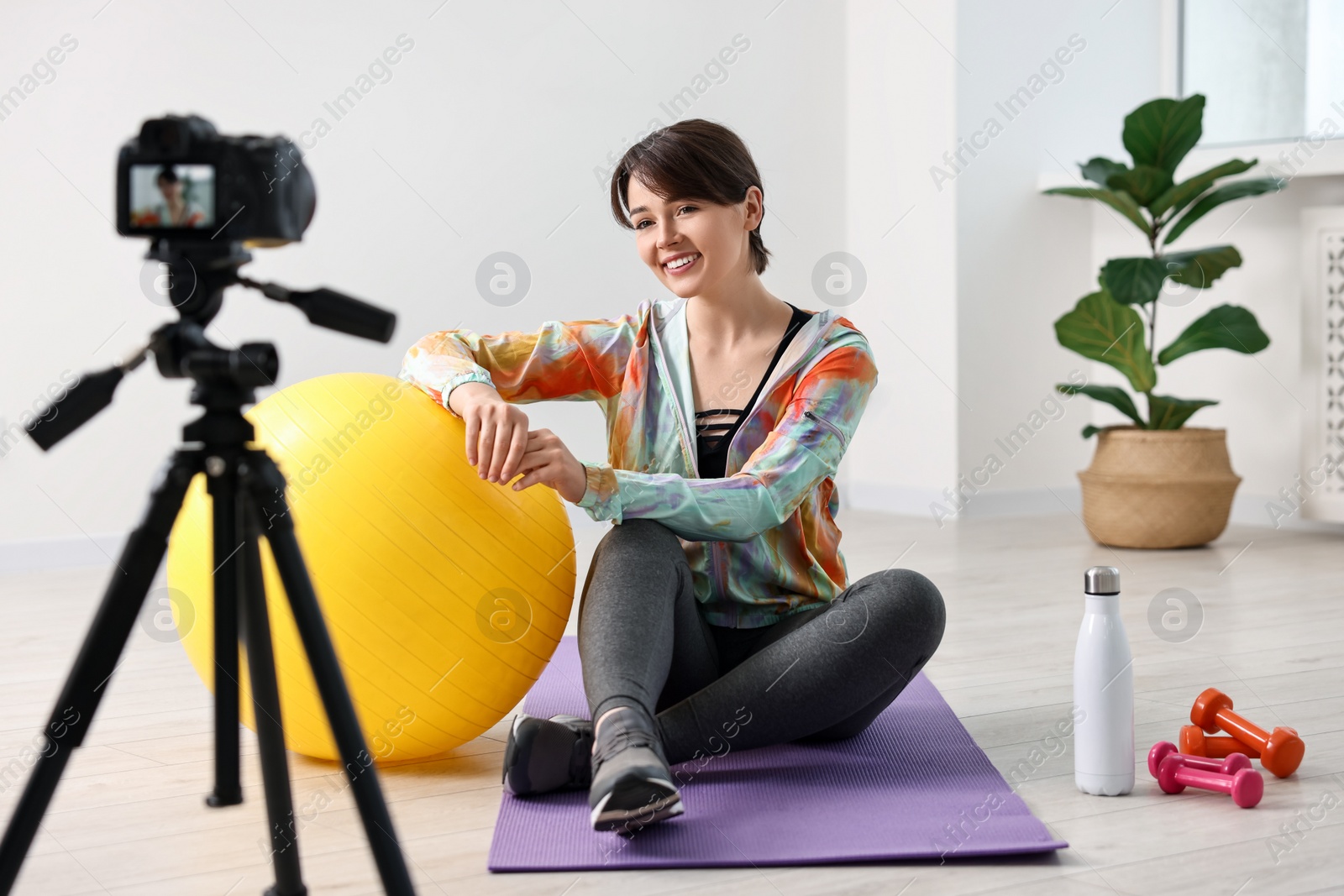 Photo of Happy sports blogger recording fitness lesson with camera at home