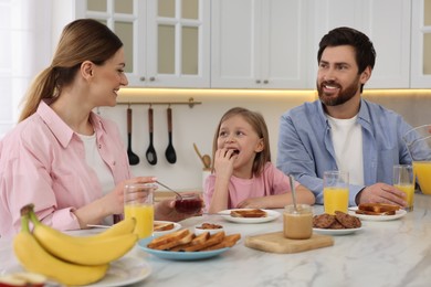 Photo of Happy family having breakfast at table in kitchen