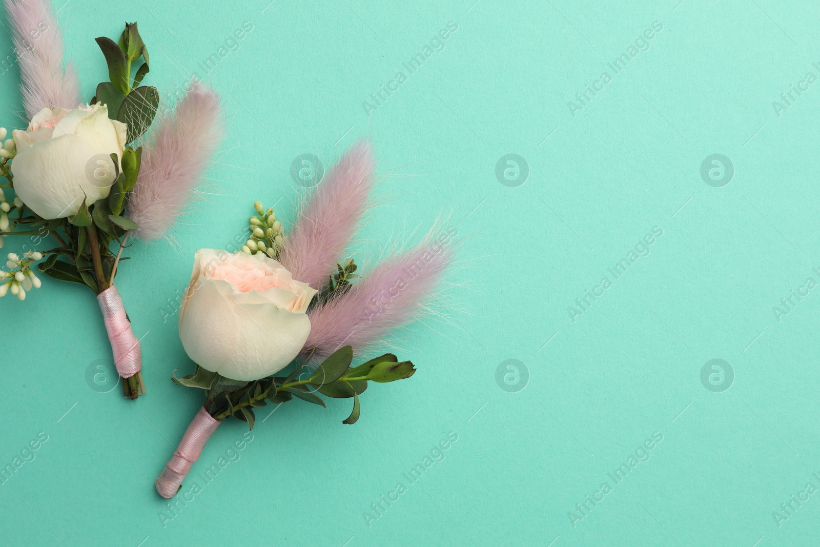 Photo of Small stylish boutonnieres on turquoise background, flat lay. Space for text