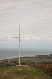 Photo of Picturesque view of beautiful sea and old cross under cloudy sky