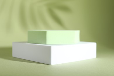 Photo of Presentation of product. Podiums and shadows on light green background. Space for text