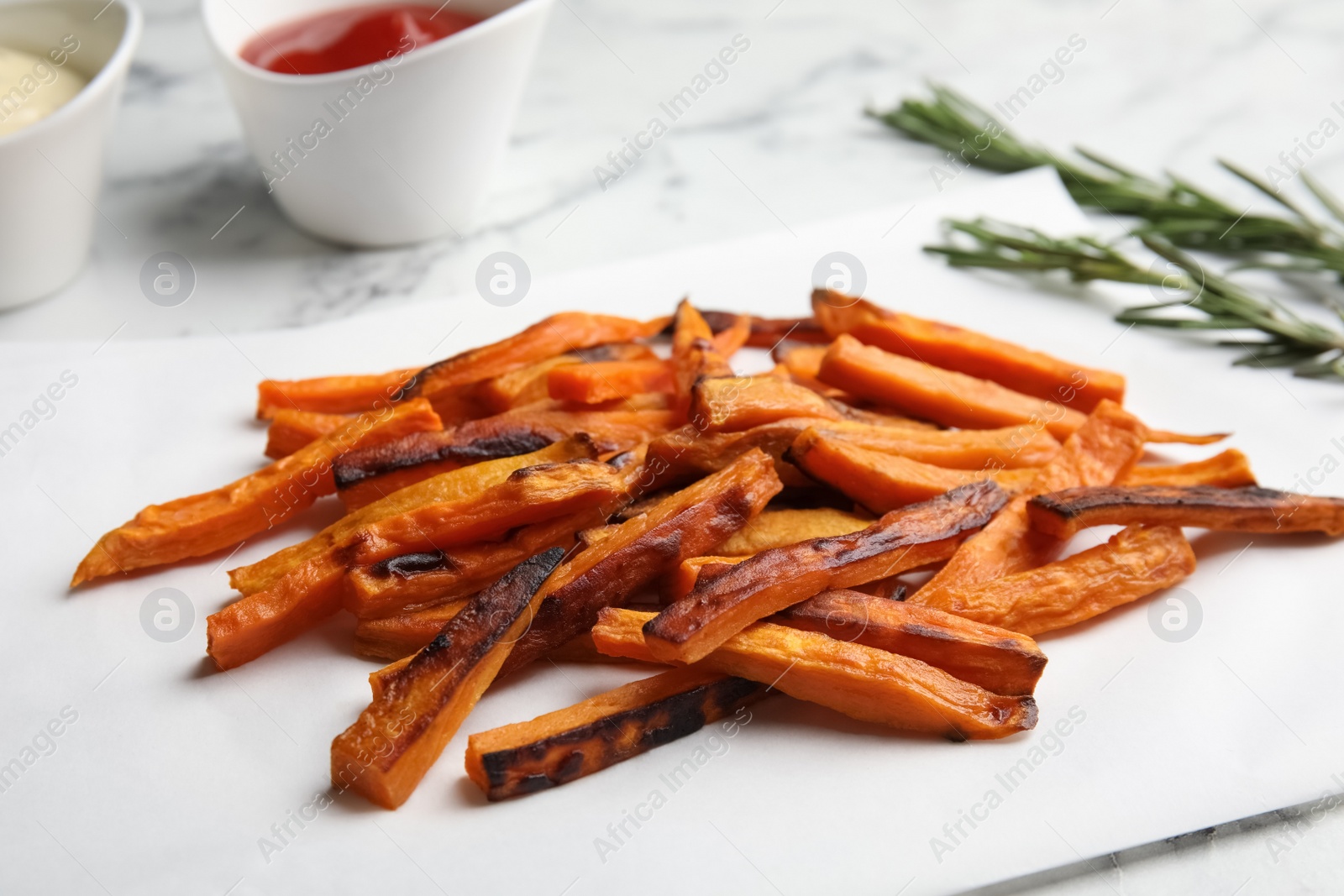 Photo of Delicious baked sweet potato slices on parchment, closeup