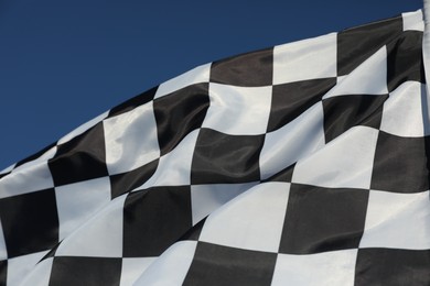 Photo of Checkered finish flag on blue background, closeup