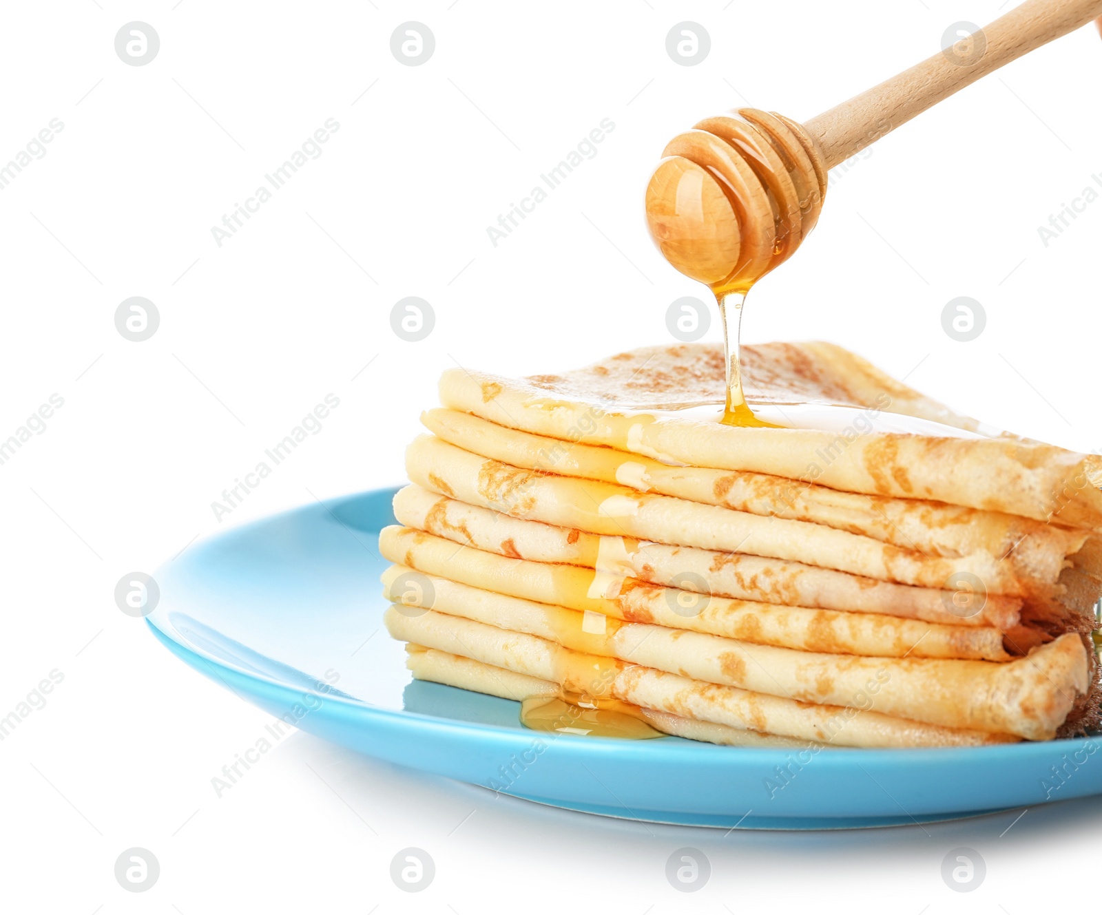 Photo of Pouring honey onto tasty thin folded pancakes on plate against white background