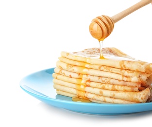Photo of Pouring honey onto tasty thin folded pancakes on plate against white background