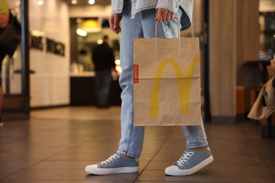 Photo of Lviv, Ukraine - September 26, 2023: Woman with McDonald's paper bag in cafe, closeup. Space for text