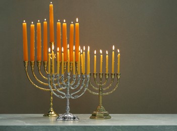 Hanukkah celebration. Menorahs with burning candles on light background, space for text