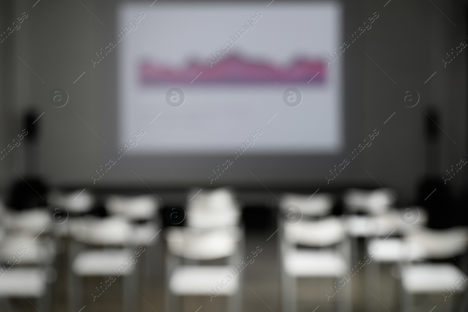 Photo of Blurred view of empty conference room with chairs and projector screen