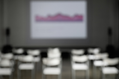 Blurred view of empty conference room with chairs and projector screen