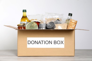 Donation box with food on wooden table