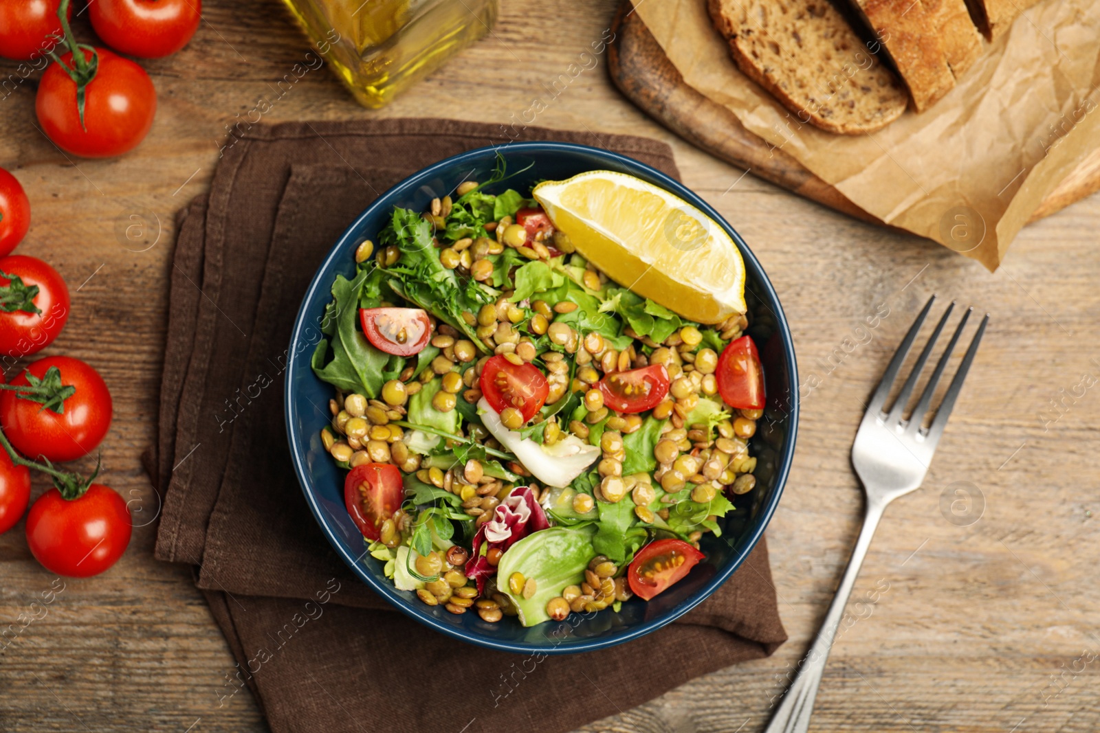 Photo of Delicious salad with lentils and vegetables served on wooden table, flat lay