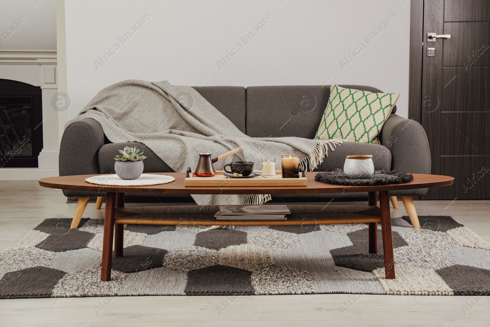 Photo of Freshly brewed coffee and decorative elements on wooden table near sofa in living room