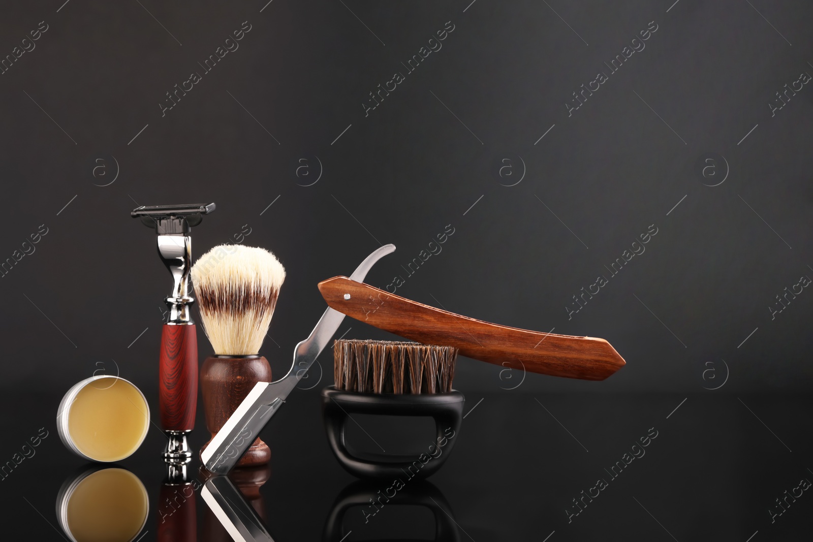 Photo of Moustache and beard styling tools on black mirror surface. Space for text