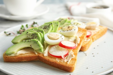 Photo of Tasty toasts with avocado, quail eggs and chia seeds on plate, closeup